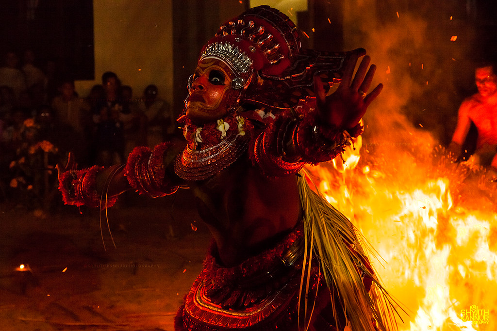 Theyyam performer dancing beside a ritual fire